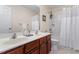 Bathroom with dual sinks and faucet with a mirror over them, wood cabinets, and shower and toilet behind at 3810 Stoneybrook Dr, Durham, NC 27705