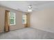 This bedroom features neutral walls, carpet, two windows with curtains, and a ceiling fan at 3810 Stoneybrook Dr, Durham, NC 27705