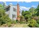 Side view of home features brick chimney, lush landscaping, and a cozy outdoor deck at 400 Bowling Creek Rd, Chapel Hill, NC 27514