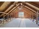 Unfinished attic space featuring exposed beams, plywood, and a window at 415 Waverly Hills Dr, Cary, NC 27519