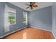 A peaceful bedroom with wood floors, two large windows, and a modern ceiling fan at 468 Hay River St, Garner, NC 27529