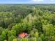 Aerial shot of house with a metal roof surrounded by green trees and lawn at 4701 Brock Dr, Hurdle Mills, NC 27541