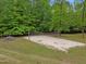Backyard with a sand volleyball court and surrounded by mature trees for shade and privacy at 4701 Brock Dr, Hurdle Mills, NC 27541