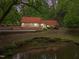 View of exterior of home with pond and surrounding trees and foliage at 4701 Brock Dr, Hurdle Mills, NC 27541