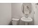 Bathroom with toilet, sink and oval mirror, with stairs visible through the doorway at 4703 Kings Garden Rd, Raleigh, NC 27612