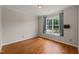 Bright, empty bedroom featuring beautiful hardwood floors, large window with curtains and ample natural light at 4703 Kings Garden Rd, Raleigh, NC 27612