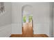 Hallway with hardwood floors, staircase with white wainscoting, and an arched doorway leading to open living space at 4703 Kings Garden Rd, Raleigh, NC 27612