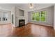 Living room with large windows, a ceiling fan, a fireplace, and hardwood floors at 4703 Kings Garden Rd, Raleigh, NC 27612