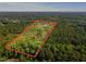 Expansive aerial shot showcases the home situated on a large wooded lot, outlined in red for property lines at 494 Asset Pkwy, Sanford, NC 27332