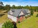Aerial view of a charming two-story home with brick accents, an attached garage, and a lush landscaped yard at 494 Asset Pkwy, Sanford, NC 27332