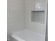A newly tiled shower featuring a built-in shelf and clean, white finishes at 502 Burton St, Fuquay Varina, NC 27526
