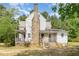 Back view of a two-story home featuring a stone chimney and a small, covered porch accessible by stairs and a lift at 5062 Dorsey Rd, Oxford, NC 27565
