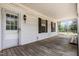 Charming covered porch with a white door, exterior light, and views of the surrounding trees at 5062 Dorsey Rd, Oxford, NC 27565