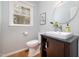 Bright bathroom featuring a square sink, round mirror, and a window providing natural light at 5312 Hallmark Rd, Durham, NC 27712