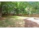 Large backyard with a privacy fence, a stone firepit, and lush, mature trees at 715 Kimbrough St, Raleigh, NC 27608