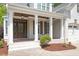 Inviting front porch with brick flooring, white columns, wood beam ceiling, and elegant lantern lighting at 715 Kimbrough St, Raleigh, NC 27608