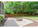 Stone patio with a cozy stone fire pit surrounded by a grass lawn and a wooden privacy fence at 715 Kimbrough St, Raleigh, NC 27608