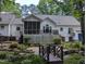 Beautiful backyard showcasing a screened porch, deck, and lush landscaping with a bridge over a pond at 7401 Walnut Grove Ln, Zebulon, NC 27597