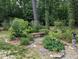 Tranquil garden featuring a stone pathway, mature trees, and a peaceful bench at 7401 Walnut Grove Ln, Zebulon, NC 27597