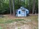 Charming white outbuilding with blue trim, perfect for a workshop or storage at 7401 Walnut Grove Ln, Zebulon, NC 27597