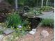 Picturesque water feature with a small bridge, koi pond, and lush landscaping at 7401 Walnut Grove Ln, Zebulon, NC 27597