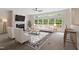 Bright living room featuring a fireplace, ceiling fan, large windows, and stylish furniture at 102 Downing Forest Pl, Cary, NC 27519