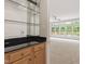 Wet bar with granite counters and glass shelves open to a bright sunroom featuring a wall of windows at 102 Downing Forest Pl, Cary, NC 27519