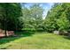Large backyard features a lush green lawn, mature trees, and metal fence at 105 Bardsey Ct, Cary, NC 27513