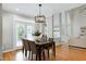 Bright dining room features a modern chandelier, wood floors, table with seating for six, and open access to living room at 105 Bardsey Ct, Cary, NC 27513