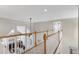 Hallway overlooks living room with fireplace and big windows, featuring wood and white railing at 105 Bardsey Ct, Cary, NC 27513