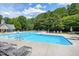 Community pool surrounded by lounge chairs, tables, umbrellas, and trees at 105 Bardsey Ct, Cary, NC 27513