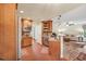 Open kitchen with wood cabinets, granite counters, brick floors, and an adjacent living room at 11 Bridgeport Dr, Durham, NC 27713
