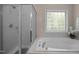 Bathroom featuring a large soaking tub, glass block window, and enclosed shower with glass doors at 11 Smoketree Ct, Durham, NC 27712