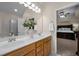 Bathroom featuring double sinks, wood cabinets, large mirror, and doorway to the main bedroom at 11 Smoketree Ct, Durham, NC 27712