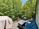 An outdoor wooden deck features cushioned wicker furniture with wooded view and glass railing at 1101 Washhouse Ln, Wake Forest, NC 27587