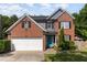 Charming brick home with a two-car garage, teal door, and well-manicured landscaping at 1101 Washhouse Ln, Wake Forest, NC 27587