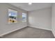 Empty bedroom with two large windows, neutral colored walls, and carpeted floors at 112 Serenata Dr, Holly Springs, NC 27540