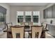 Bright dining area with large windows, stylish curtains, and modern gray cabinetry for functional storage at 112 Serenata Dr, Holly Springs, NC 27540