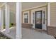 A covered front porch welcomes you, framed by elegant white columns and brick accents, with a black front door at 112 Serenata Dr, Holly Springs, NC 27540