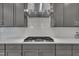 A kitchen features gray cabinets, subway tile backsplash, stainless steel range hood, and quartz countertops at 112 Serenata Dr, Holly Springs, NC 27540