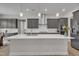 Bright kitchen with large island, stainless steel appliances, gray cabinets, and modern pendant lights at 112 Serenata Dr, Holly Springs, NC 27540