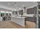 An open kitchen and dining area features stainless appliances, an island and gray cabinets at 112 Serenata Dr, Holly Springs, NC 27540