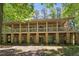 Stunning home showcasing a full-length covered porch with beautiful stone pillars and wooded surroundings at 11470 Club Dr, Chapel Hill, NC 27517