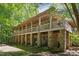 Stunning home showcasing a full-length covered porch with beautiful stone pillars and wooded surroundings at 11470 Club Dr, Chapel Hill, NC 27517
