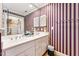 Bathroom featuring a double sink vanity, striped wallpaper, and a view into the closet at 11477 Club Dr, Chapel Hill, NC 27517