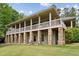 Multi-story home with large deck supported by stone columns and a large grassy yard at 11483 Club Dr, Chapel Hill, NC 27517