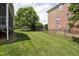 Lush, green backyard with well-manicured lawn, iron fencing, and the side of a brick home at 11916 Deneb Ct, Raleigh, NC 27614