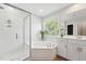 Bright bathroom featuring a glass shower, soaking tub, vanity, and large window at 11916 Deneb Ct, Raleigh, NC 27614