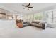 Open-concept living room with a gray sofa, bright windows, and a view into the modern kitchen and dining area at 11916 Deneb Ct, Raleigh, NC 27614