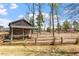 Rustic log cabin-style shed in a grassy backyard with wooden fencing and scattered trees under a clear sky at 12 Beacon Ridge Blvd, Chapel Hill, NC 27516